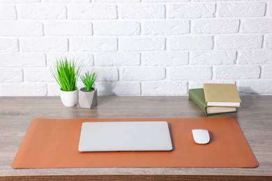 Photo of Stylish workplace with laptop and orange mousepad on wooden table indoors. Space for text