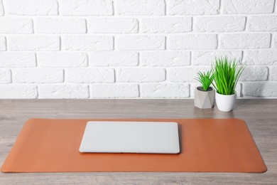 Photo of Stylish workplace with laptop and orange mousepad on wooden table indoors. Space for text
