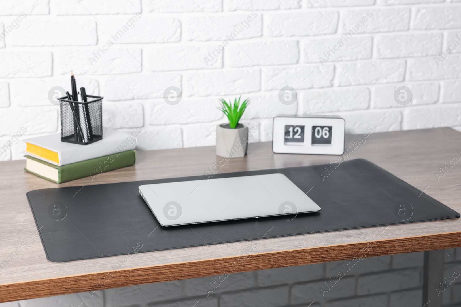 Stylish workplace with laptop and black mousepad on wooden table indoors Photo of Stylish workplace with laptop and black mousepad on wooden table indoors
