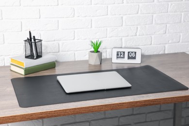 Photo of Stylish workplace with laptop and black mousepad on wooden table indoors