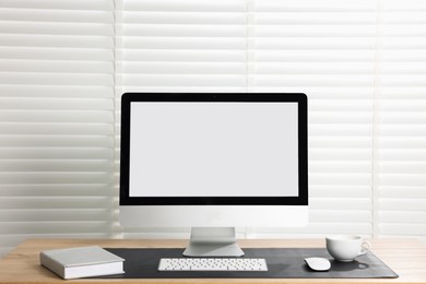 Photo of Stylish workplace with computer and black mousepad on wooden table indoors. Space for text