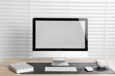 Photo of Stylish workplace with computer and black mousepad on wooden table indoors. Space for text