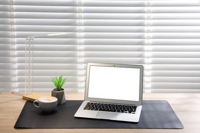 Photo of Stylish workplace with laptop and black mousepad on wooden table indoors. Space for text