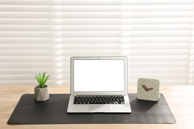 Photo of Stylish workplace with laptop and black mousepad on wooden table indoors. Space for text