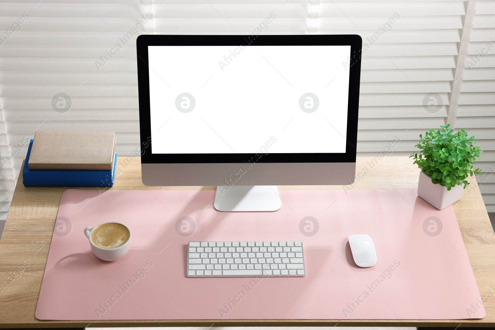 Photo of Stylish workplace with computer and pink mousepad on wooden table indoors. Space for text