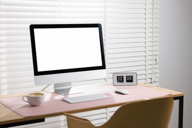 Photo of Stylish workplace with computer and pink mousepad on wooden table indoors. Space for text