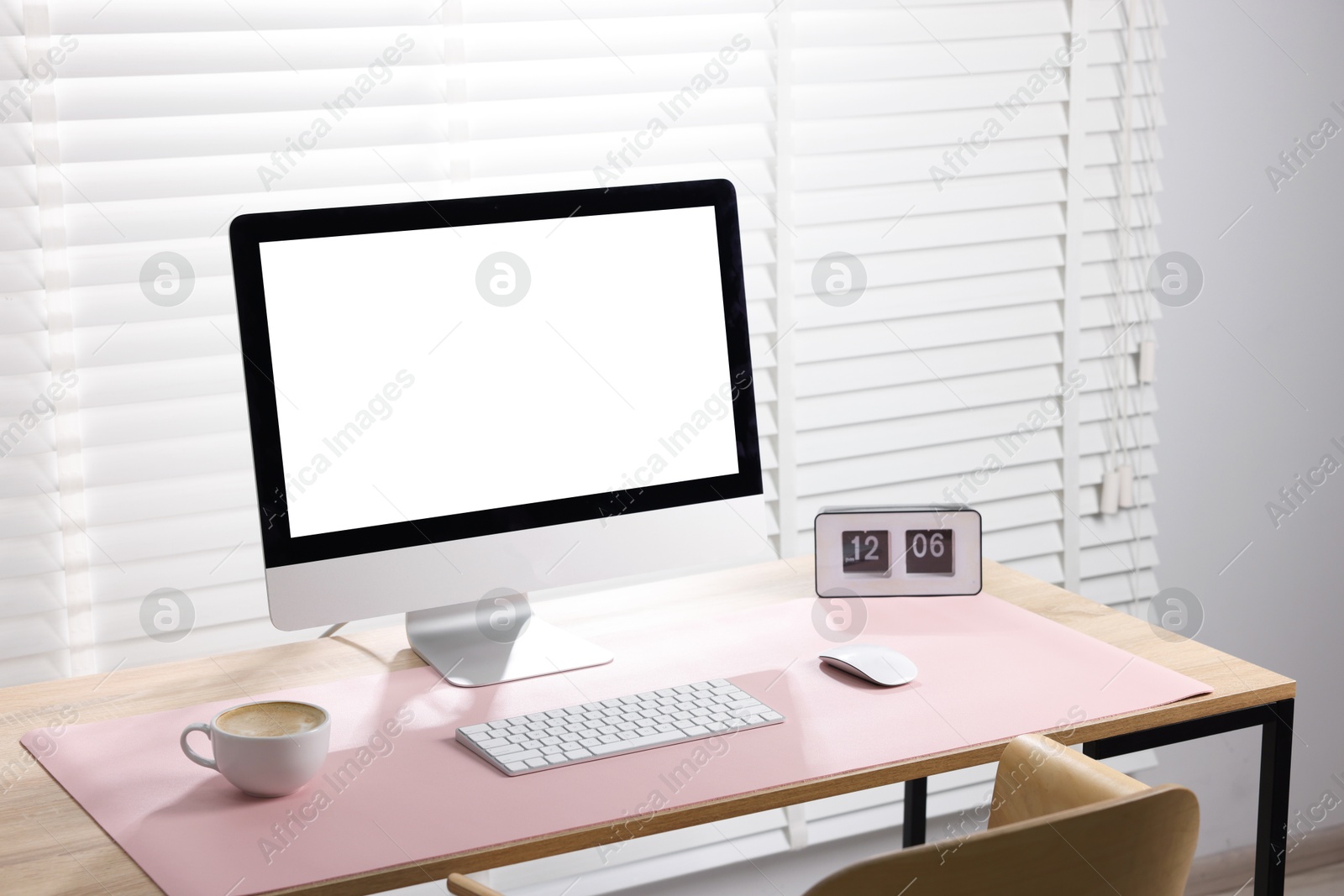 Photo of Stylish workplace with computer and pink mousepad on wooden table indoors. Space for text