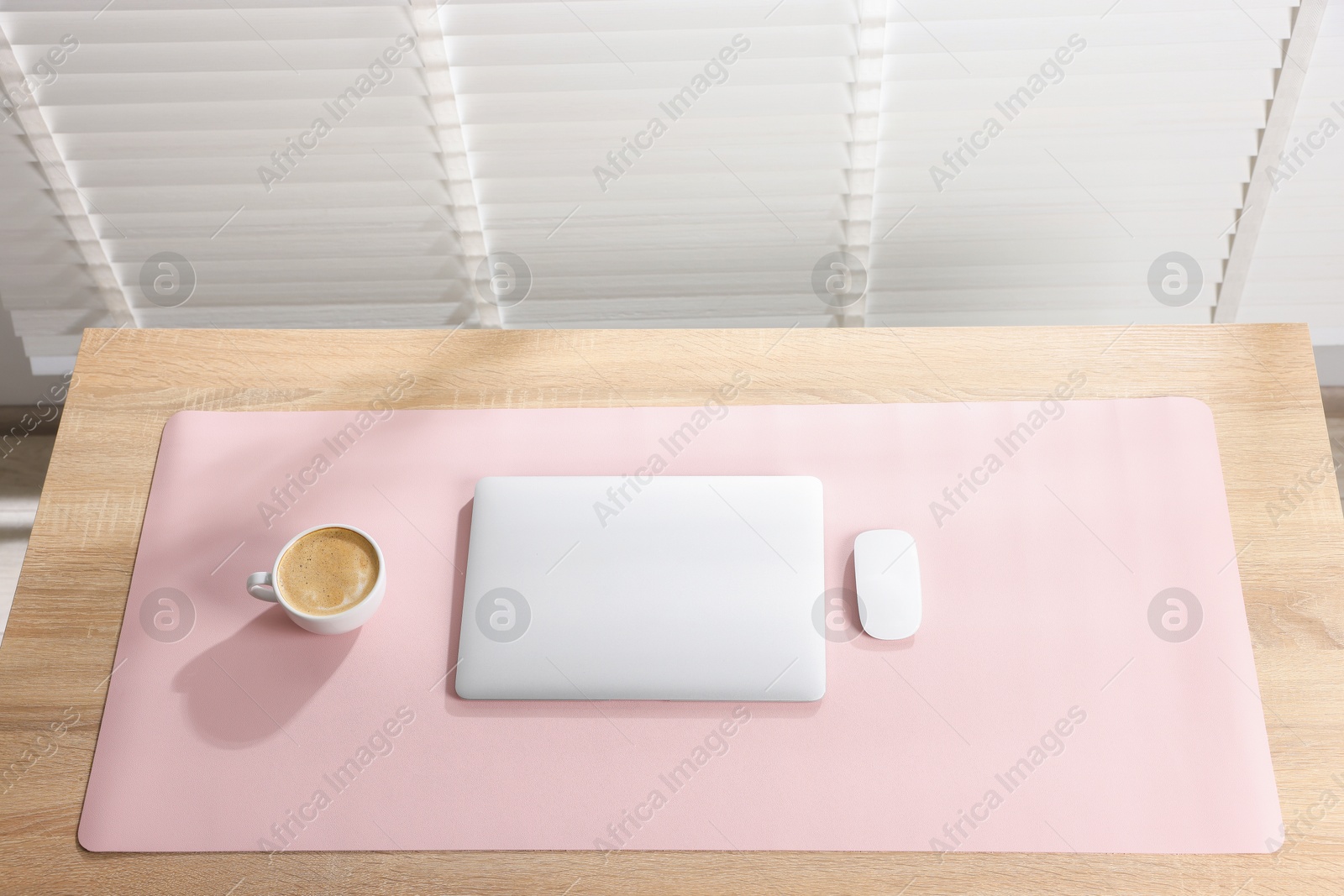 Photo of Stylish workplace with laptop and pink mousepad on wooden table indoors, above view