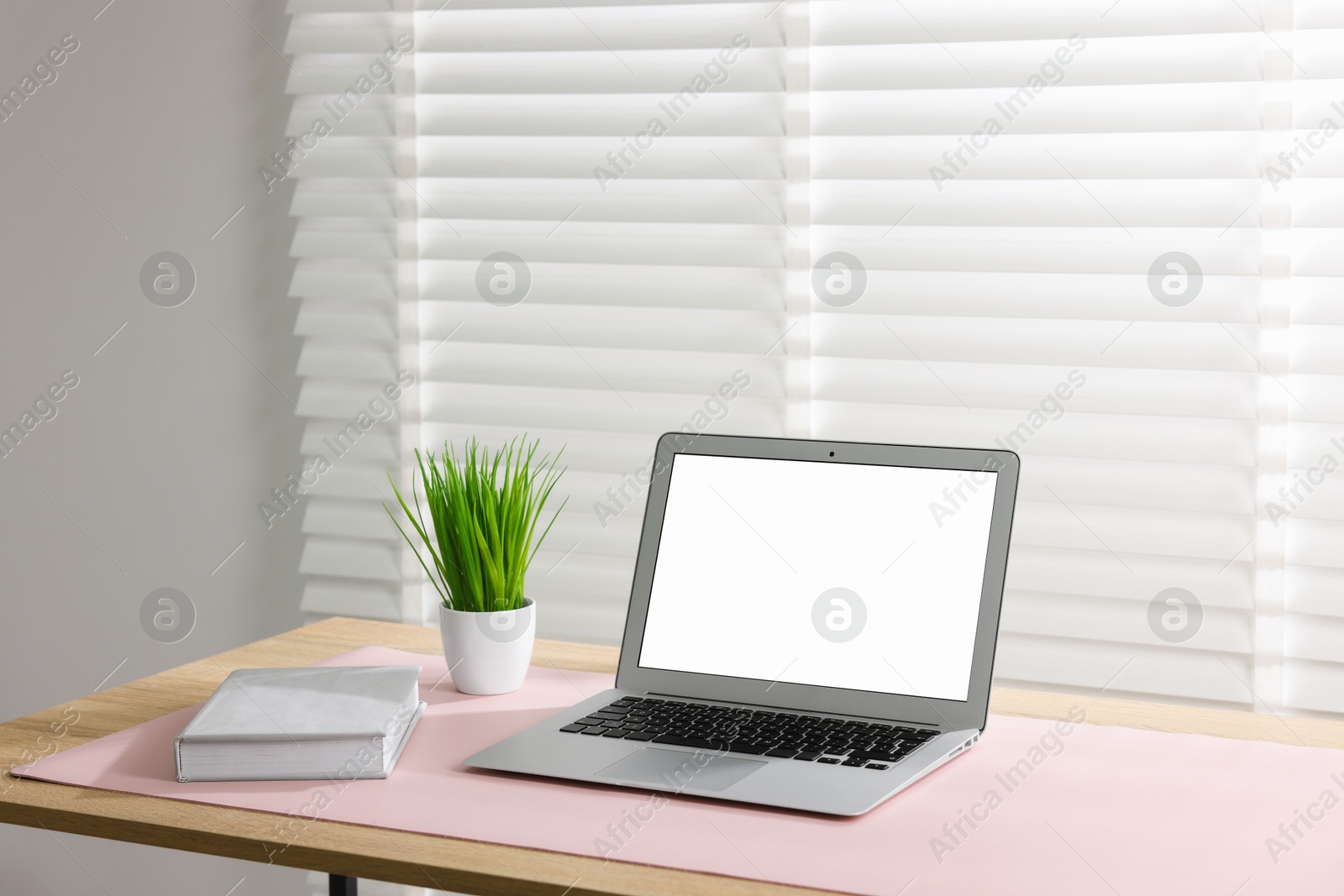 Photo of Stylish workplace with laptop and pink mousepad on wooden table indoors. Space for text