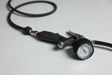 Photo of One tire inflation gun with gauge on light background, closeup