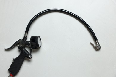 Photo of One tire inflation gun with gauge on light background, top view