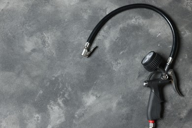 Photo of One tire inflation gun with gauge on grey background, top view. Space for text
