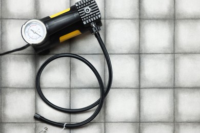 Photo of One tire inflation gun with gauge on light tiled background, top view. Space for text