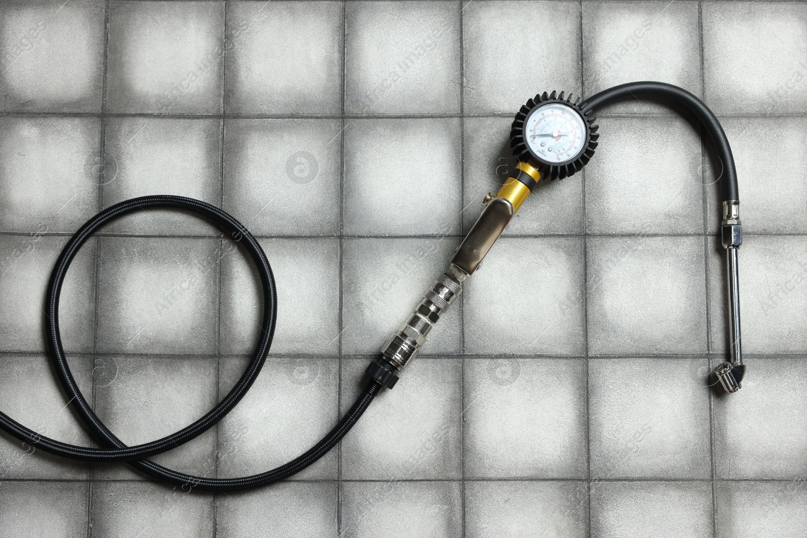 One tire inflation gun with gauge on light tiled background, top view Photo of One tire inflation gun with gauge on light tiled background, top view
