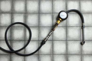 Photo of One tire inflation gun with gauge on light tiled background, top view