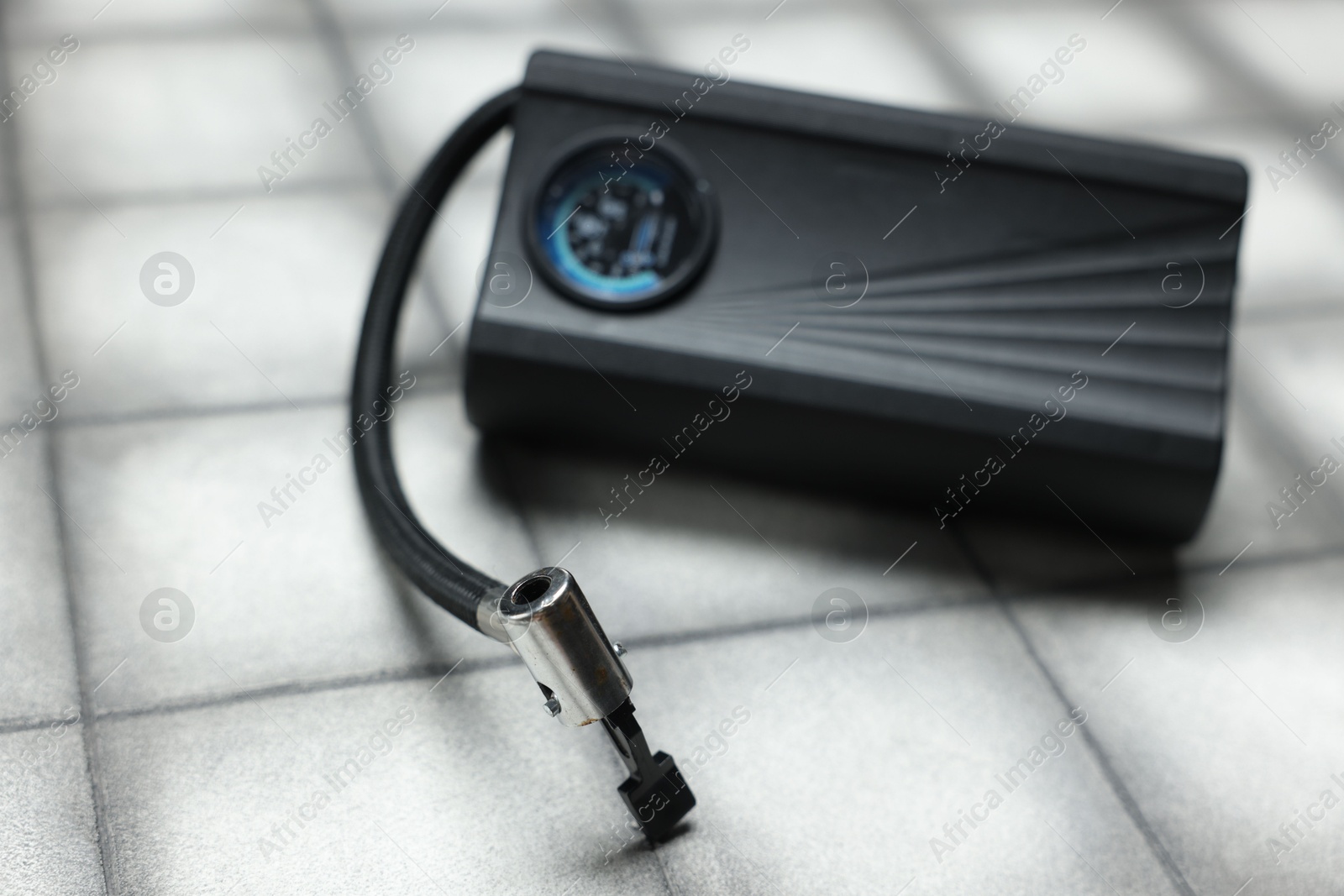 Photo of One modern tire inflator on light tiled background, closeup