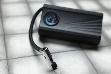 Photo of One modern tire inflator on light tiled background, closeup