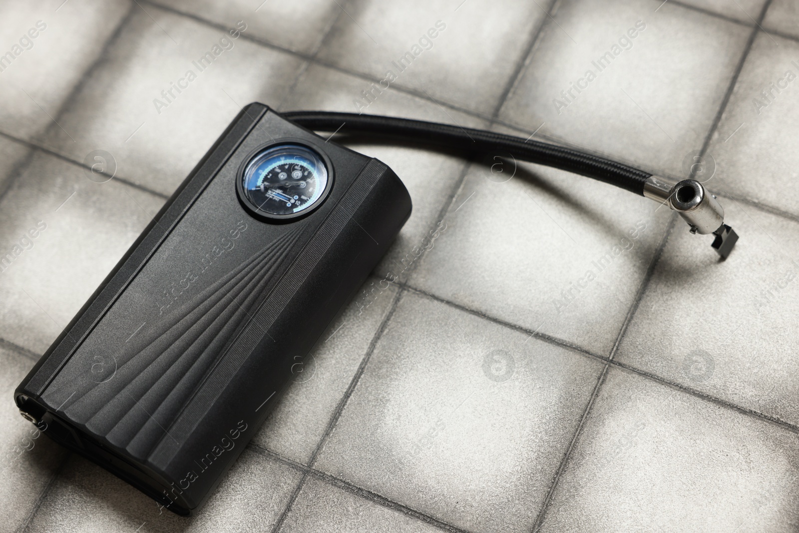 Photo of One tire inflator on light tiled background, closeup