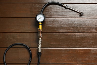 Photo of One tire inflation gun with gauge on wooden background, top view. Space for text