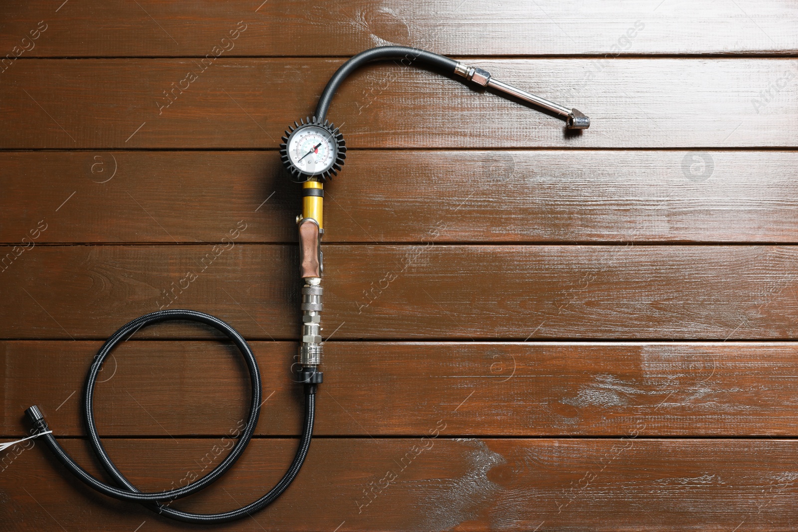 Photo of One tire inflation gun with gauge on wooden background, top view. Space for text