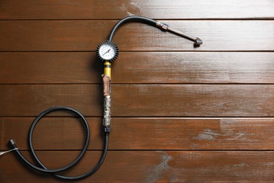 Photo of One tire inflation gun with gauge on wooden background, top view. Space for text