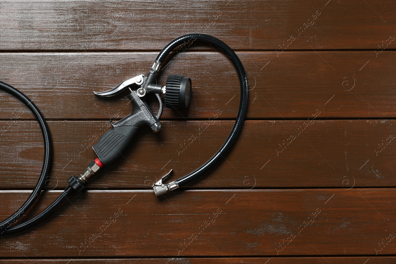 Photo of One tire inflation gun with gauge on wooden background, top view