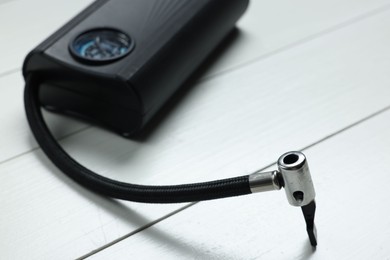 Photo of One modern tire inflator on white wooden background, closeup