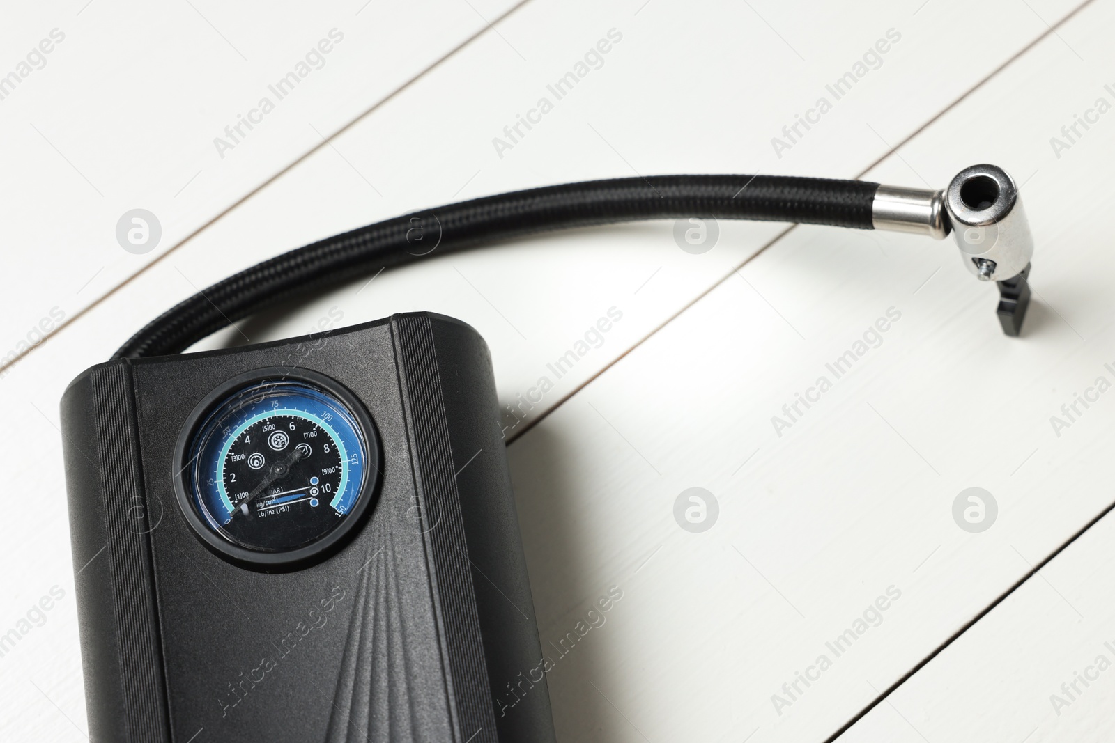 Photo of One modern tire inflator on white wooden background, closeup