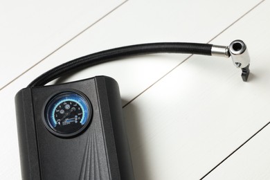 Photo of One modern tire inflator on white wooden background, closeup