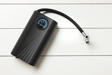 Photo of One modern tire inflator on white wooden background, top view