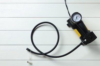 Photo of One tire inflator on white wooden background, top view
