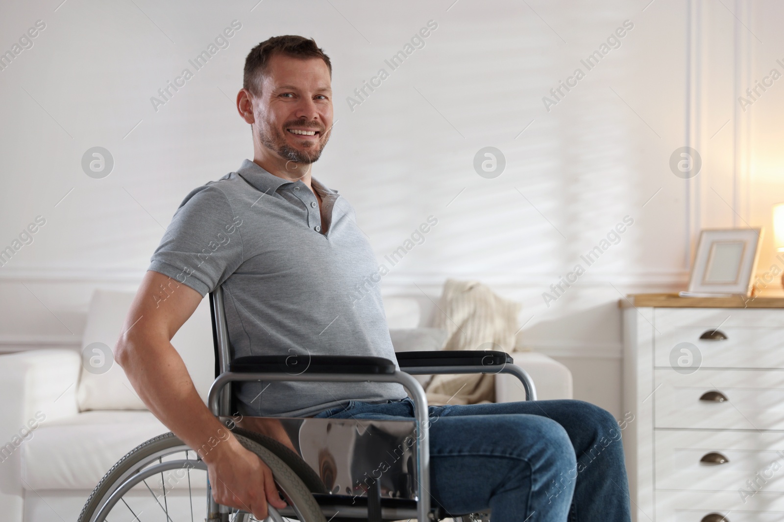 Photo of Happy man in modern wheelchair at home