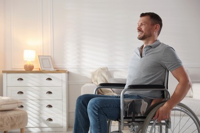 Photo of Happy man in modern wheelchair at home, space for text