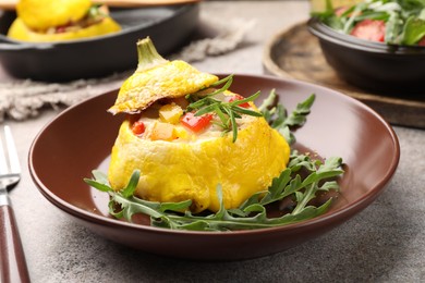 Photo of Tasty stuffed pattypan squash with arugula served on grey table, closeup