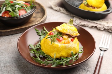 Photo of Tasty stuffed pattypan squash with arugula served on grey table, closeup