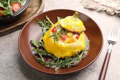 Photo of Tasty stuffed pattypan squash with arugula served on grey table, closeup