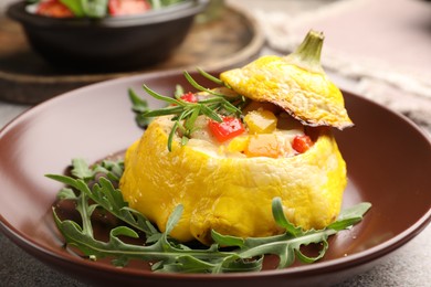 Photo of Tasty stuffed pattypan squash with arugula on grey table, closeup