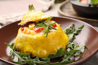 Photo of Tasty stuffed pattypan squash with arugula on grey table, closeup