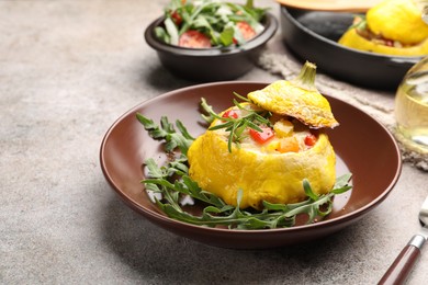 Photo of Tasty stuffed pattypan squash with arugula served on grey table, closeup