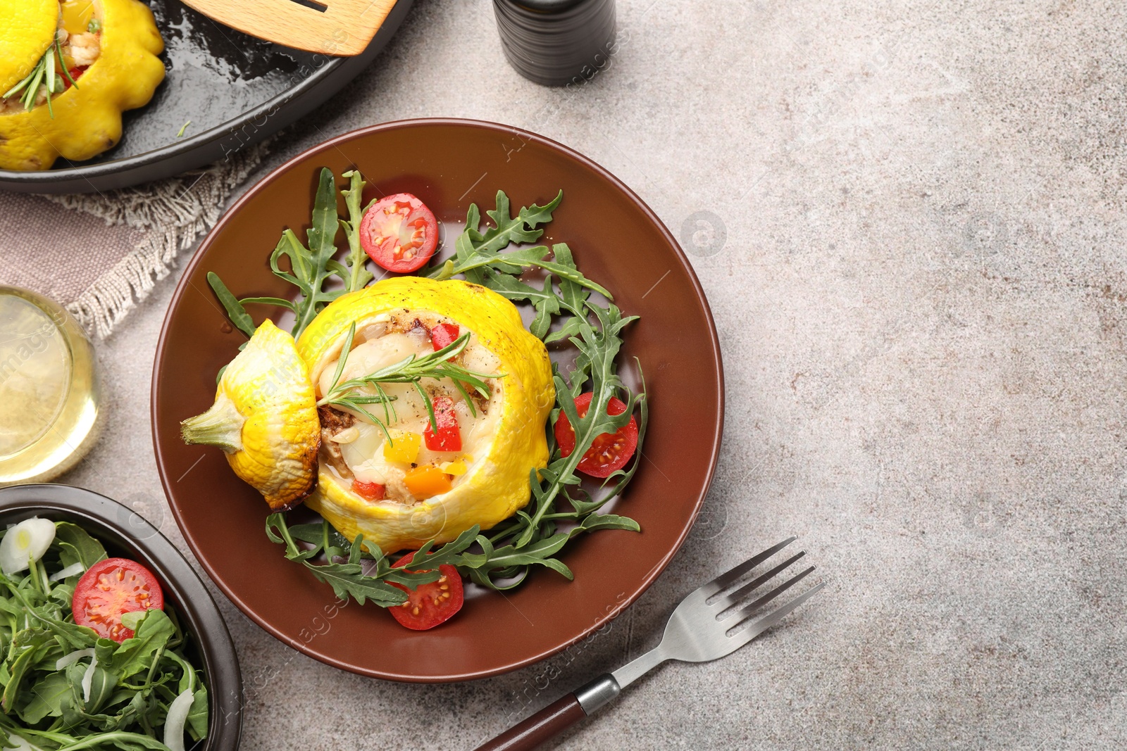 Photo of Tasty stuffed pattypan squash with tomatoes and arugula served on grey table, flat lay. Space for text