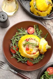 Photo of Tasty stuffed pattypan squash with tomatoes and arugula served on grey table, flat lay