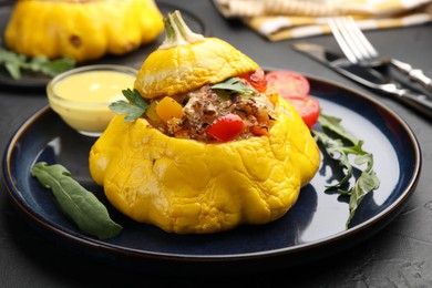 Photo of Tasty stuffed pattypan squash with sauce on black table, closeup
