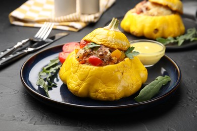Photo of Tasty stuffed pattypan squash with sauce on black table, closeup