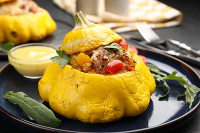Photo of Tasty stuffed pattypan squash with sauce on black table, closeup