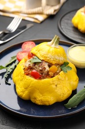 Photo of Tasty stuffed pattypan squash with sauce on black table, closeup