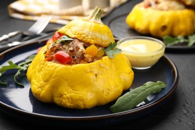 Photo of Tasty stuffed pattypan squash with sauce on black table, closeup