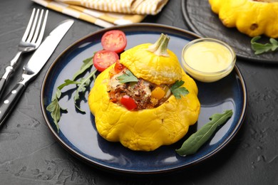 Photo of Tasty stuffed pattypan squash with sauce served on black table, closeup