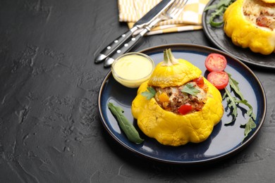 Photo of Tasty stuffed pattypan squash with sauce served on black table. Space for text
