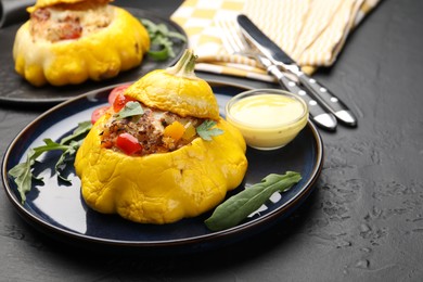 Photo of Tasty stuffed pattypan squash with sauce served on black table, closeup