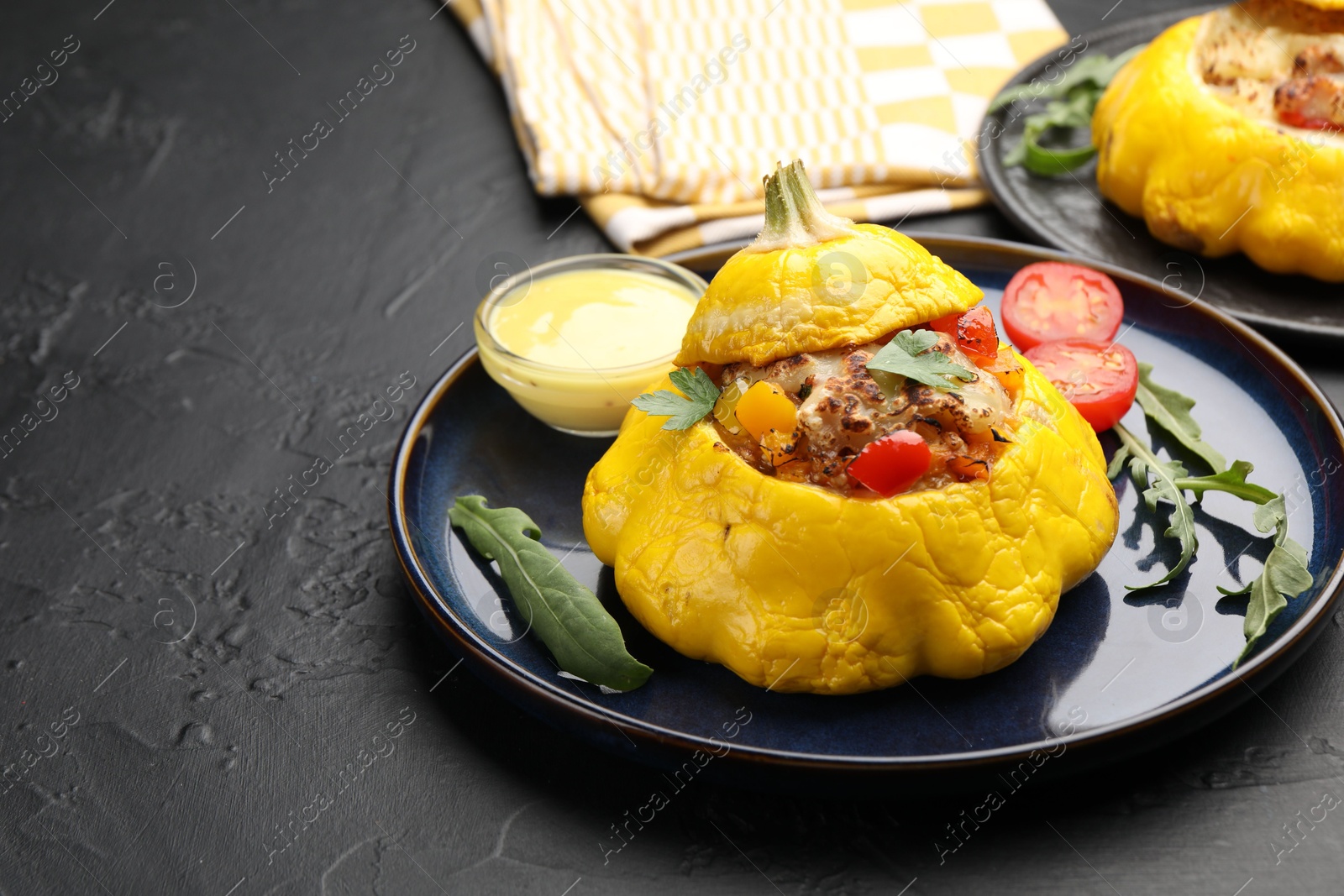 Photo of Tasty stuffed pattypan squash with sauce on black table, closeup. Space for text